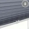 A close-up view of a gray pleated blind with a white handle and a circular icon with arrows indicating up and down movement. Produktbild-Vorschau