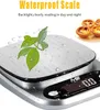 A digital kitchen scale with water droplets on its surface and a small plant on top. In the background, there are some pastries. Produktbild-Vorschau