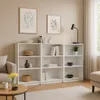 A white bookshelf filled with books and decorative items in a living room setting. Produktbild-Vorschau