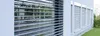 A modern building exterior with multiple windows covered by roller shutters. Produktbild-Vorschau