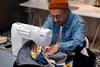 A person is using a sewing machine to sew fabric. Produktbild-Vorschau
