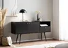 A black sideboard with oak-effect details is displayed in a living room setting, adorned with a lamp, vase, and books. Podgląd zdjęcia produktu