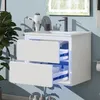 A white bathroom vanity with two drawers is mounted on a light blue wall. The drawers are slightly open, revealing blue LED lighting inside. A black faucet is installed on the white countertop. A white hairdryer is mounted on the wall to the left of the va Produktbild-Vorschau