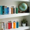 Several glass water bottles with protective sleeves are displayed on white shelves, alongside books and a globe. Anteprima dell’immagine prodotto