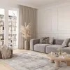 A modern living room with a gray sofa, a round wooden coffee table, and a patterned rug. Anteprima dell’immagine prodotto