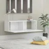 A white wall-mounted TV cabinet with its doors open, displaying two compartments. A white desk lamp is on the left, and a decorative sphere and books are on the right. A potted plant is visible on the right side of the image, and two pillows are on the flo Náhľad obrázku produktu