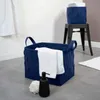 A dark blue woven storage basket with white towels inside, placed on a gray floor next to a black soap dispenser and a white bath pouf. Another smaller basket is on a black stool in the background. Podgląd zdjęcia produktu