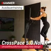 A woman is using an elliptical trainer in a modern living room with a TV in the background. Podgląd zdjęcia produktu