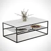 A white coffee table with a black metal frame, featuring a glass vase with branches and a small plate with purple items on top. Produktbild-Vorschau