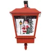 A red Christmas lantern with a scene of Santa Claus, a Christmas tree, and a lamppost inside, set against a snowy background. Náhľad obrázku produktu