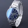 A close-up shot of a silver and blue analog wristwatch with a metal band, set against a dark, textured background. Produktbild-Vorschau