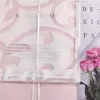 A close-up view of a white sheer curtain with a pink floral pattern, overlaid on a pink background. A bouquet of pink roses is visible on the right side. Produktbild-Vorschau