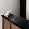 A close-up of a wooden counter with a black top and a menu holder on it. Produktbild-Vorschau