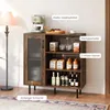 A rustic-style sideboard with a glass door, wine rack, and wine glass holder, shown in a home setting with a lamp and rug. Náhľad obrázku produktu