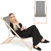 A woman is sitting on a foldable deck chair and holding a mug. Produktbild-Vorschau