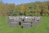 An outdoor lounge set with a sofa, table, and ottomans on a grassy lawn with trees in the background. Produktbild-Vorschau