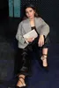 A woman sitting on the floor, holding a clutch. Produktbild-Vorschau