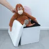 A hand is placing a stuffed orangutan into a white storage cube. Náhled obrázku produktu