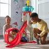 Two children are playing with a Paw Patrol toy tower and race track in a room with Paw Patrol themed wallpaper. Náhľad obrázku produktu