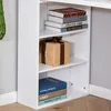 A white bookcase filled with books and a gift-wrapped package. Voir les images du produit