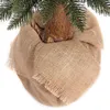Close-up of the base of a Christmas tree, showing the trunk wrapped in burlap. Náhled obrázku produktu