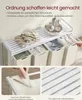 A white metal laundry sorter with four beige fabric bins, featuring a top shelf with towels and toiletries. Close-up shots show the bin attachment and the slatted shelf design. Produktbild-Vorschau