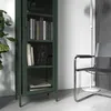 A green metal display cabinet filled with books and decorative items, next to a chair and a floor lamp. Produktbild-Vorschau