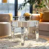 A mirrored round coffee table with a glass vase of flowers on top, placed on a plush rug in a living room setting. Anteprima dell’immagine prodotto