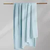 A light blue textured blanket is draped over a wooden rod against a plain background. Podgląd zdjęcia produktu