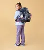 A young girl wearing a backpack and looking over her shoulder. Náhľad obrázku produktu