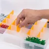 A hand is shown sorting small parts into a transparent organizer box with orange dividers. Voir les images du produit