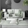A living room scene featuring a couch, coffee table, rug, and decorative items. Podgląd zdjęcia produktu