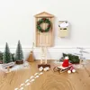 A miniature Christmas-themed scene with a small wooden door, wreath, ladder, broom, sled, and footprints on a wooden floor. Produktbild-Vorschau