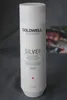 A white bottle of Goldwell Dualsenses Silver Shampoo is shown against a gray background. A blurred image of a person is visible in the background. Náhľad obrázku produktu