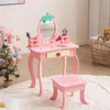 A child's pink vanity table and stool are set up in a room with toys and decorations. Produktbild-Vorschau