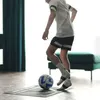 A person is practicing soccer drills indoors on a mat with a soccer ball. Podgląd zdjęcia produktu