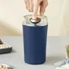 A hand presses a button on a dark blue electric grinder. Produktbild-Vorschau