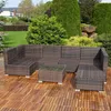 A polyrattan lounge set with a sofa, ottoman, and table is placed on a wooden deck in a garden setting. Náhled obrázku produktu