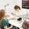 A nail technician is applying nail polish to a customer's nails at a manicure table. Voir les images du produit