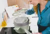A woman is cooking with a pot on a stovetop. Anteprima dell’immagine prodotto