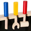 A close-up view of wooden toy tools, including a hammer, wrench, and screwdriver, attached to a wooden board. Náhled obrázku produktu