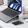A Satechi Bluetooth numeric keypad is placed on a desk next to a laptop, a cup of coffee, and wireless earbuds. Voir les images du produit