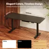 A black standing desk with dimensions indicated, shown in a room with wooden walls and floor, and a plant in the background. Color options are displayed at the bottom. Produktbild-Vorschau