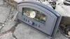 A cast iron pizza oven door with a glass window and thermometer, lying on a stone surface outdoors. Produktbild-Vorschau