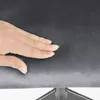 A hand is pressing down on a dark gray fabric surface, likely demonstrating the softness or cushioning of the material. Voir les images du produit