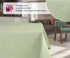 A tablecloth is shown on a table in a living room setting, with a close-up inset showing water droplets on the fabric. Produktbild-Vorschau