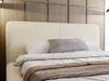 A close-up view of a bed with a beige headboard and bedding. Produktbild-Vorschau