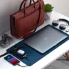 A desk setup with a laptop, briefcase, headphones, camera, and charging accessories. Produktbild-Vorschau