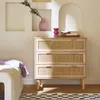 A dresser with rattan drawer fronts is shown in a room with a bed and a rug. Produktbild-Vorschau