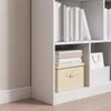 A close-up view of a white bookshelf with books and storage boxes. Produktbild-Vorschau